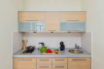 a kitchen with wooden cabinets and a sink at 1-Bedroom Flat on the Main Square in the Old Town in Kotor