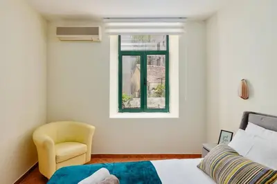 a bedroom with a bed and a chair and a window at 1-Bedroom Flat on the Main Square in the Old Town in Kotor