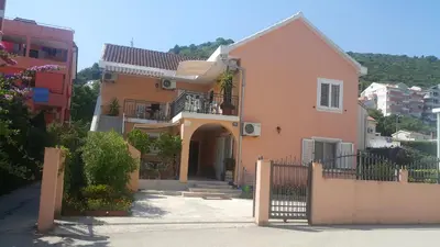 a pink house with a gate and a fence at Sobe Nedović in Budva