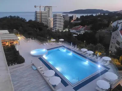 a swimming pool with chairs and umbrellas on a building at Status-M Apartments 103 in Becici