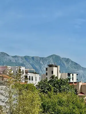 a group of white buildings with mountains in the background at Budva - Becici in Becici