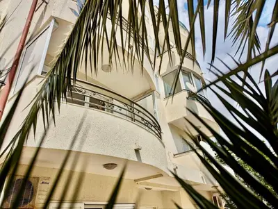 a building with a balcony and a palm tree at Budva - Becici in Becici