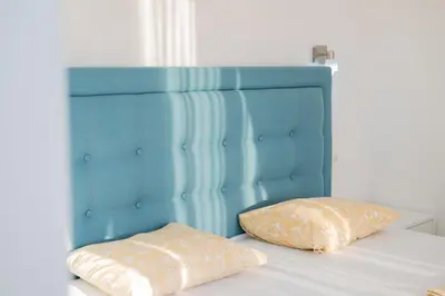 a bed with a blue headboard and two pillows on it at Apartments Chiara Garden in Ulcinj