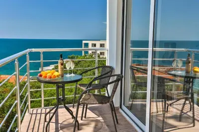 a balcony with a table and chairs and the ocean at Buskovic Bella Vista in Dobra Voda