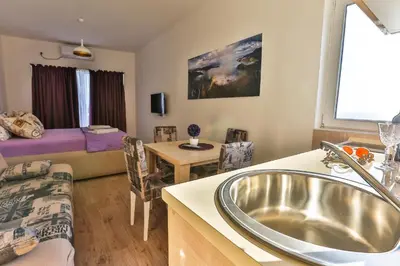 a bathroom with a sink and a living room with a couch at Buskovic Bella Vista in Dobra Voda