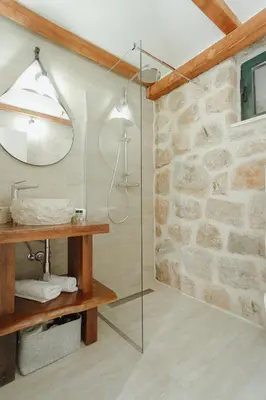 a glass shower in a bathroom with a stone wall at Casa di Pietra in Kotor