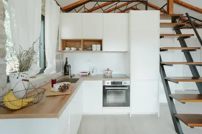 a kitchen with white cabinets and a spiral staircase at Casa di Pietra in Kotor
