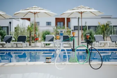 a pool with chairs and umbrellas next to a swimming pool at Imperial Family Bungalows in Ulcinj