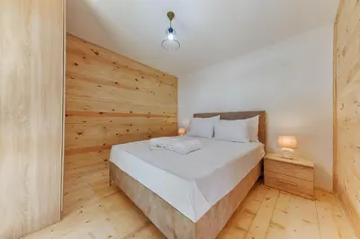 a bedroom with a bed with a wooden wall at Imperial Family Bungalows in Ulcinj