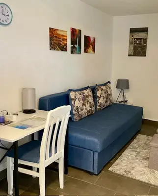 a blue couch in a living room with a table and a desk at Sutomore Panorama Apartment in Sutomore