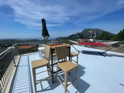 a balcony with a table and chairs and an umbrella at Sutomore Panorama Apartment in Sutomore