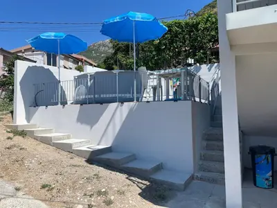 two blue umbrellas sitting on top of a white fence at Sutomore Panorama Apartment in Sutomore