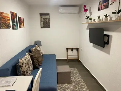 a living room with a blue couch and a tv at Sutomore Panorama Apartment in Sutomore