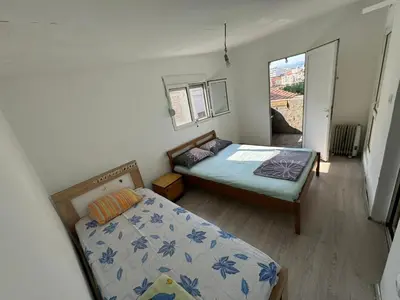 a small bedroom with two beds and a window at Vlado apartments in Podgorica