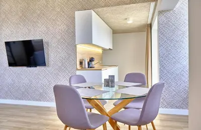 a dining room with a glass table and purple chairs at Apartments Magic box II in Utjeha