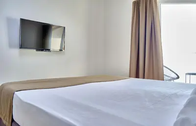 a bedroom with a bed with a tv on the wall at Apartments Magic box II in Utjeha
