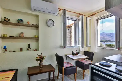 a kitchen with a table and chairs and a clock on the wall at Basilica Apartments in Budva