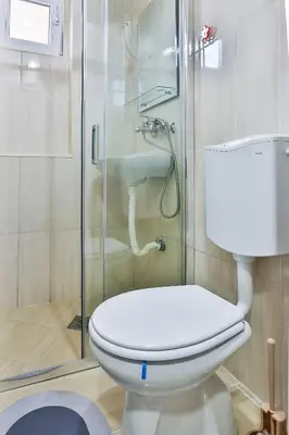 a bathroom with a toilet and a glass shower at Basilica Apartments in Budva