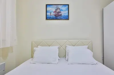 a bed with white pillows and a picture on the wall at Basilica Apartments in Budva