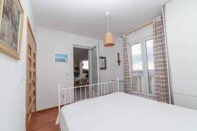 a white bedroom with a bed and a window at Beachfront First Line View in Sveti Stefan