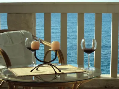 a table with two glasses of wine on a balcony at Beachfront First Line View in Sveti Stefan