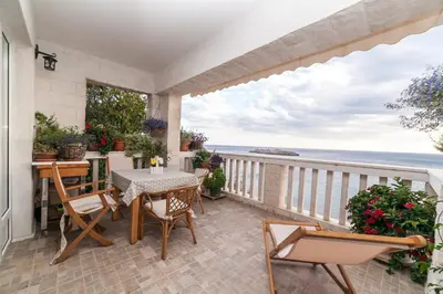 a patio with a table and chairs and the ocean at Beachfront First Line View in Sveti Stefan