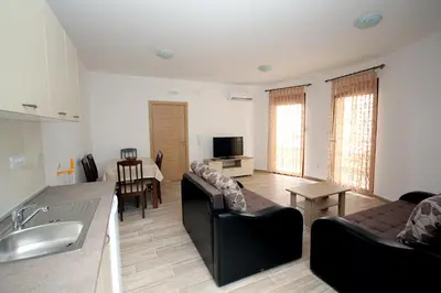 a kitchen and living room with a couch and a table at Apartments Md Lux in Sutomore
