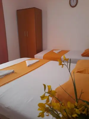 two twin beds in a room with a clock on the wall at Apartments Aza in Dobra Voda