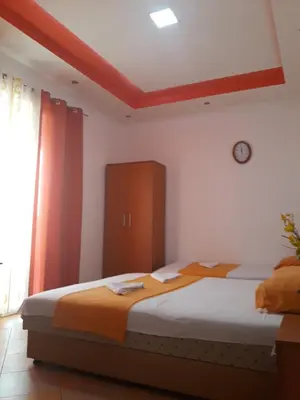 a bedroom with two beds and a clock on the wall at Apartments Aza in Dobra Voda