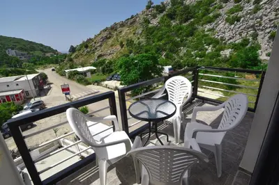 a balcony with white chairs and a table and a mountain at Apartments A Čanj in Čanj