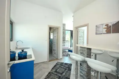 a kitchen with a sink and a counter with stools at Apartments A Čanj in Čanj
