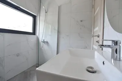 a white bathroom with a sink and a window at Apartments A Čanj in Čanj
