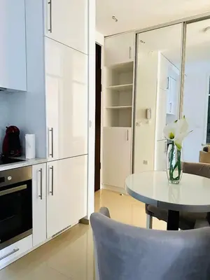a white kitchen with a table and a vase of flowers at Nora Apartment in Budva