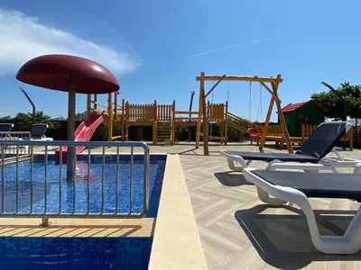 a pool with a playground with chairs and an umbrella at Imperial Family Resort in Ulcinj