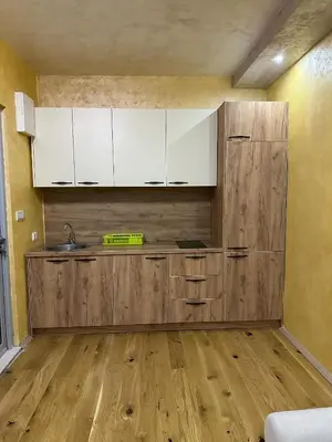 a kitchen with white cabinets and a wooden floor at Lux Apartment Oasis in Rafailovici