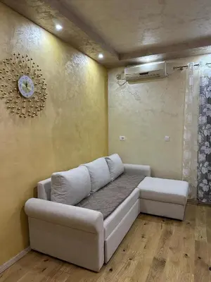 a living room with a couch and a clock on the wall at Lux Apartment Oasis in Rafailovici