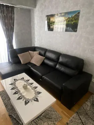 a black leather couch in a living room with a table at Adriatic apartman in Budva