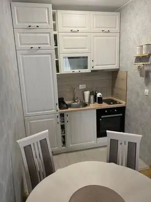 a kitchen with white cabinets and a table and a sink at Adriatic apartman in Budva