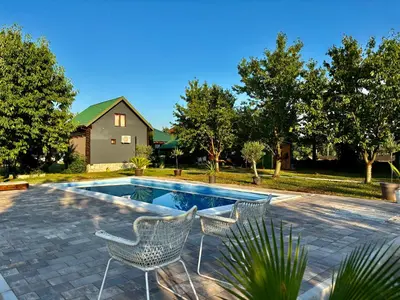 a swimming pool with two chairs and a house at Tiny house 1 - Imanje Terzic in Podgorica