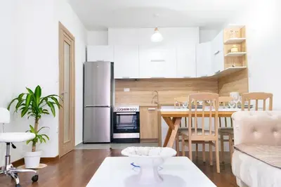 a kitchen and living room with a table and a refrigerator at Ana Lux Master apartament in Podgorica
