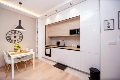 a kitchen with white cabinets and a table and a clock at Comfort apartment Becici by In Property in Becici