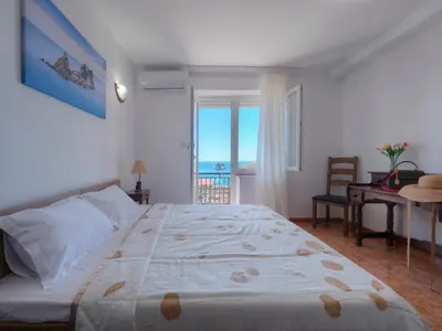 a bedroom with a large bed with a view of the ocean at Casa Pastrovici del Mare in Petrovac na Moru