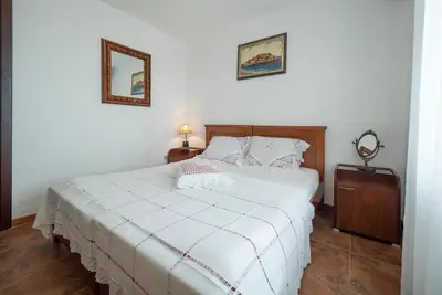 a bedroom with a large white bed with two pictures on the wall at Casa Pastrovici del Mare in Petrovac na Moru