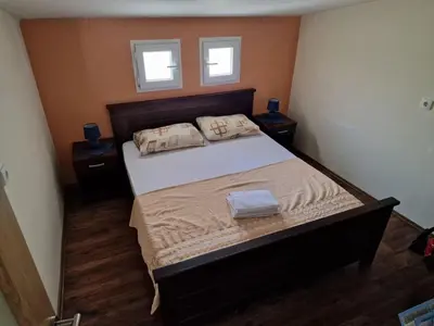 a bedroom with a large bed with two windows at Lakeside oasis home Karuc in Karuč
