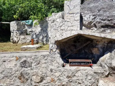 a stone fireplace with a bench in a stone wall at Lakeside oasis home Karuc in Karuč