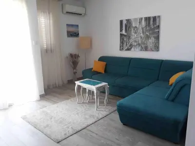 a living room with a blue couch and a table at APARTMAN PAVLE in Petrovac na Moru