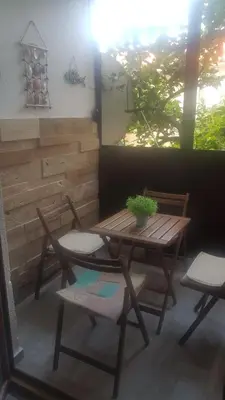 a patio with a wooden table and chairs and a window at APARTMAN PAVLE in Petrovac na Moru