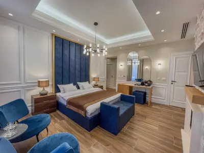 a bedroom with a king sized bed and blue chairs at Hive Luxury Suites by MN Property in Kotor