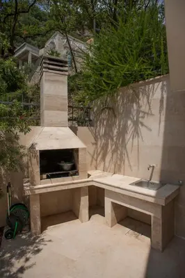 a stone bench with a fireplace in a backyard at Apartments Villa Simonovic in Petrovac na Moru