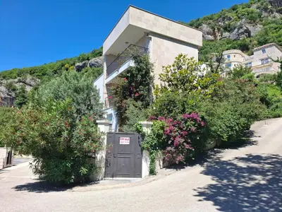 a building with a gray door and some flowers at Apartments Villa Simonovic in Petrovac na Moru